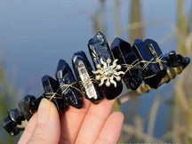 Black crystal point tiara with a gold-tone sun face and contrasting metallic wrapping around the dark points.