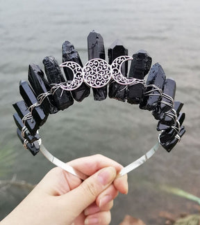 Front view of a black crystal point crown with a silver-tone triple moon emblem and wire-wrapped band.