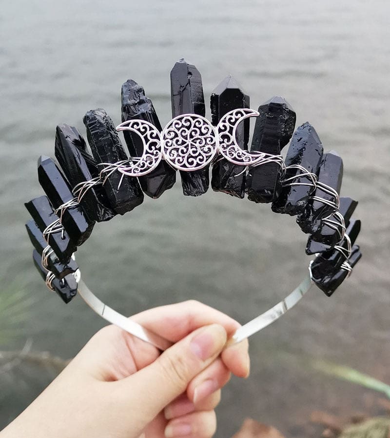 Front view of a black crystal point crown with a silver-tone triple moon emblem and wire-wrapped band.