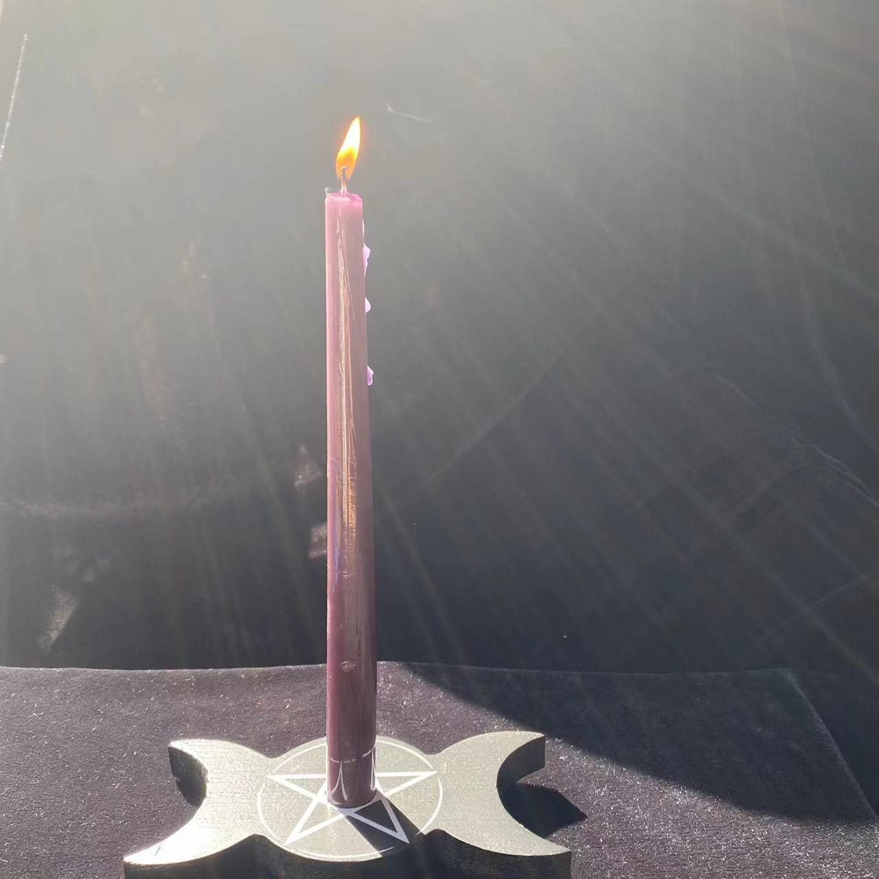 Full view of a pink taper rising from the triple moon holder, showing the flat black base beneath the long candle.