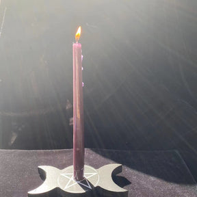 Full view of a pink taper rising from the triple moon holder, showing the flat black base beneath the long candle.