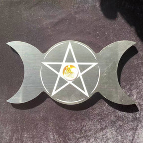 Overhead view of the black triple moon holder with a candle in its centre and white pentagram linework across the round middle.
