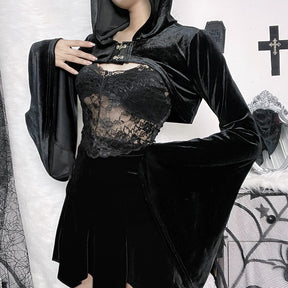 The black velvet bolero modeled with the hood raised and one arm bent, displaying a broad pointed bell cuff. A lace camisole is styled underneath.