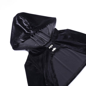 Black velvet hooded bolero laid flat on white, showing the hood opening, cropped body and two ornate front clasps.
