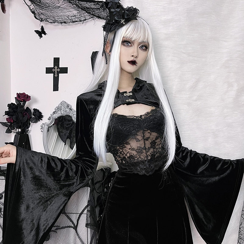 Model with long white hair wearing the velvet bolero with the hood down and both arms extended. Wide bell sleeves frame a separate lace camisole and black skirt.