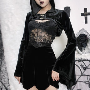 Black hooded velvet bolero shown in a gothic outfit with a lace camisole and short skirt, standing beside an ornate white mirror and dark wall decorations.