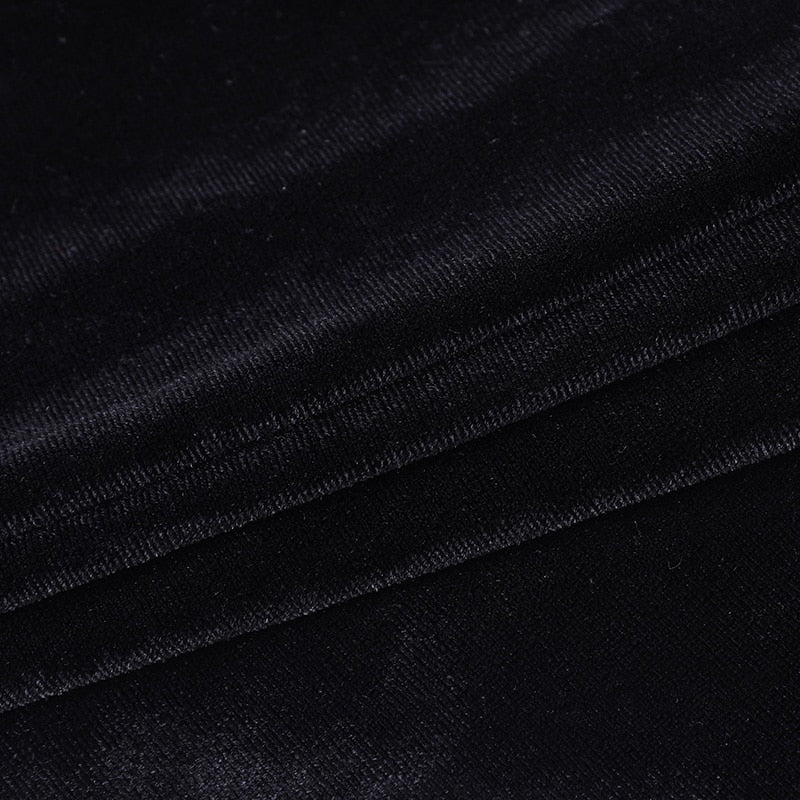 Close-up of black velvet fabric on the bolero, showing its short pile, directional sheen and stitched edge.