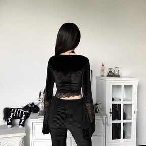 Rear view of the plain black velvet crop top with floral lace along the lower hem and sheer lace sections across the long sleeves.