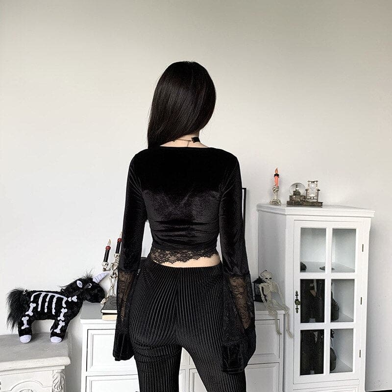 Rear view of the plain black velvet crop top with floral lace along the lower hem and sheer lace sections across the long sleeves.