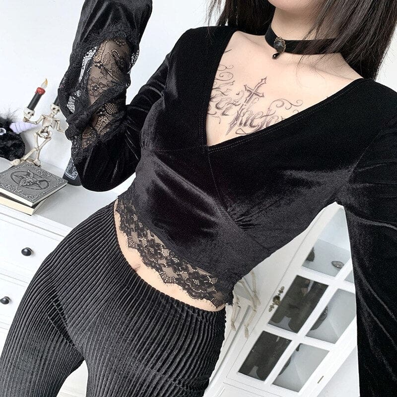 Angled close-up of the velvet V-neck, wide floral lace hem and a raised bell sleeve above black pinstripe trousers.