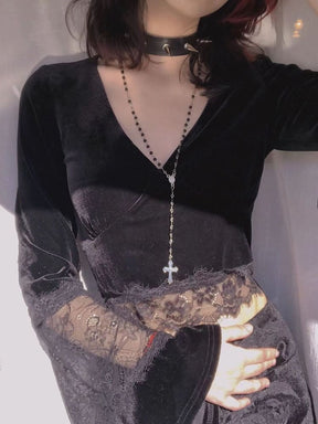 A model wears the deep V-neck velvet crop top with a long pendant necklace, showing the wide lace hem and one sweeping cuff.
