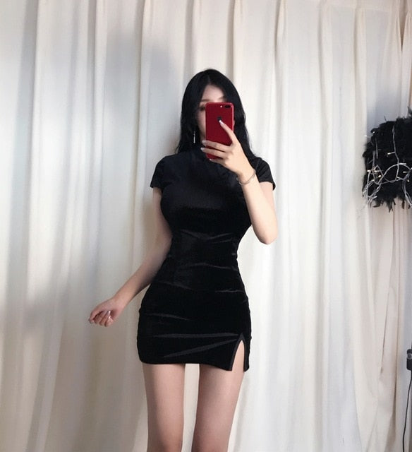 Black mandarin-collar velvet mini dress shown in a mirror outfit photo against pale curtains.