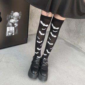 Black over-the-knee stockings with white bats shown in a closer view of the legs and black cuffs.