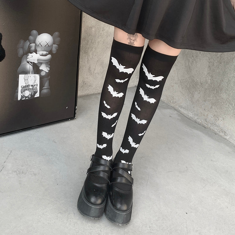 Black over-the-knee stockings with white bats shown in a closer view of the legs and black cuffs.