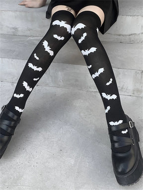 Black over-the-knee stockings with white bats worn in a seated pose with the bat pattern visible.