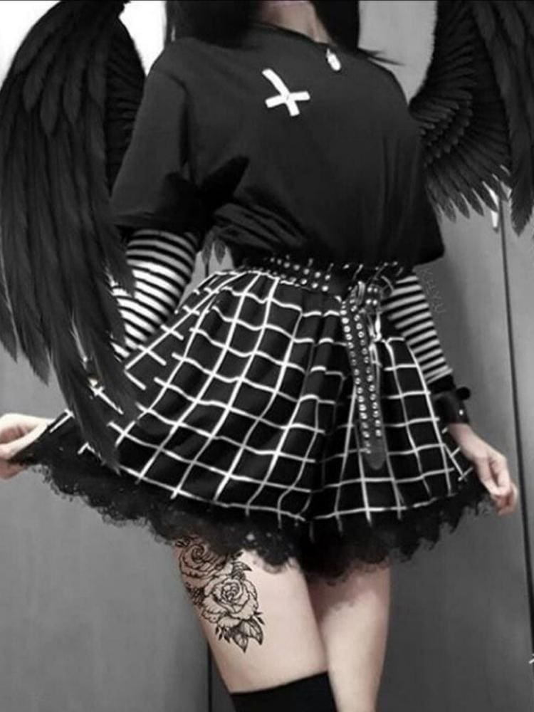 Black high-waisted skort worn from the front, with a white grid pattern flaring over the short hem and scalloped black lace beneath. A striped sleeve and studded belt complete the styled outfit.