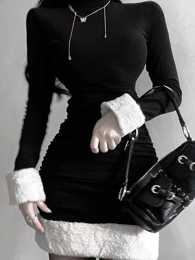 Black holiday mini dress with white fluffy cuffs and hem styled with a black bag, front view.