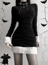 Black holiday mini dress with white fluffy cuffs and hem worn from the front against a bat-decorated backdrop.
