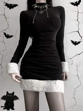 Black holiday mini dress with white fluffy cuffs and hem worn from the front against a bat-decorated backdrop.