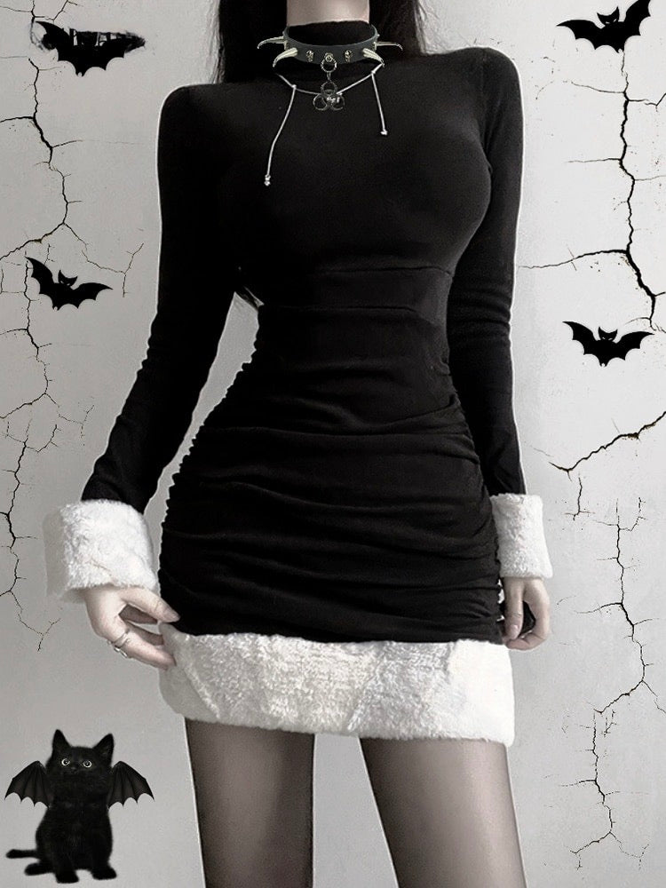 Black holiday mini dress with white fluffy cuffs and hem worn from the front against a bat-decorated backdrop.