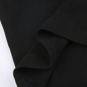 Black holiday mini dress with white fluffy cuffs and hem with a close view of a stitched seam in the ribbed fabric.