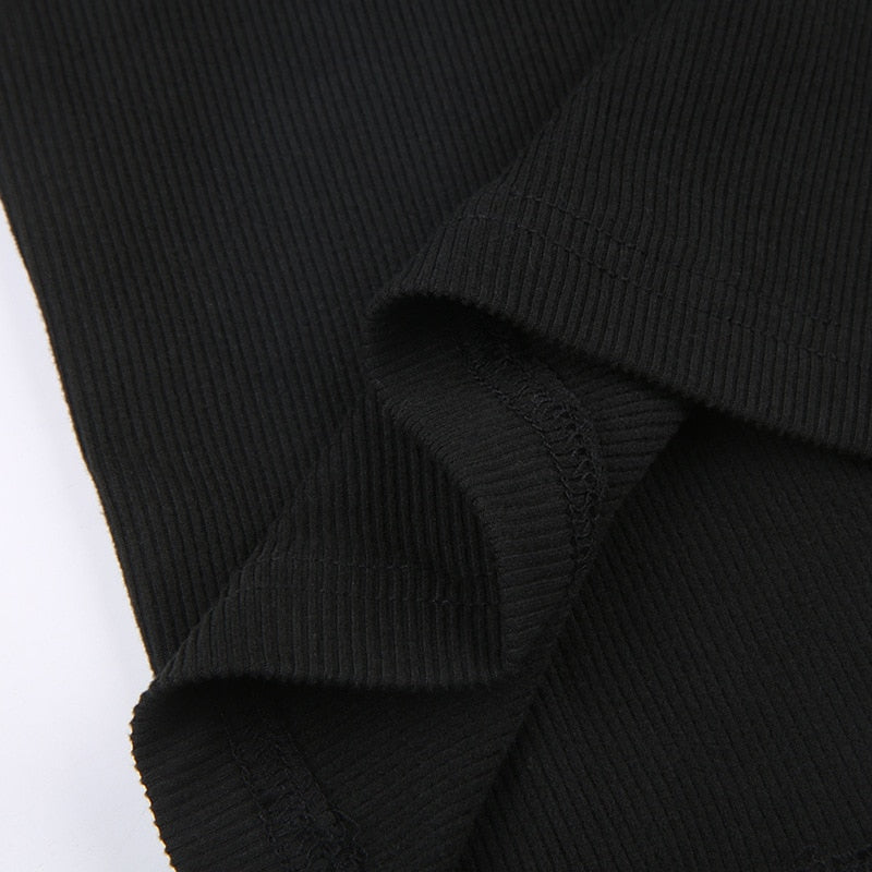 Black holiday mini dress with white fluffy cuffs and hem with a close view of a stitched seam in the ribbed fabric.