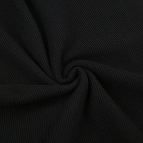 Black holiday mini dress with white fluffy cuffs and hem with a close view of the fine black ribbed texture.