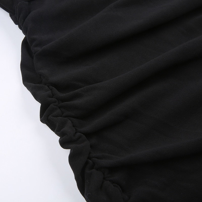 Black holiday mini dress with white fluffy cuffs and hem with a close view of the gathered side seam.
