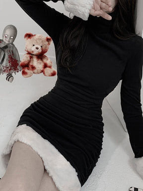 Black holiday mini dress with white fluffy cuffs and hem shown in a seated pose.