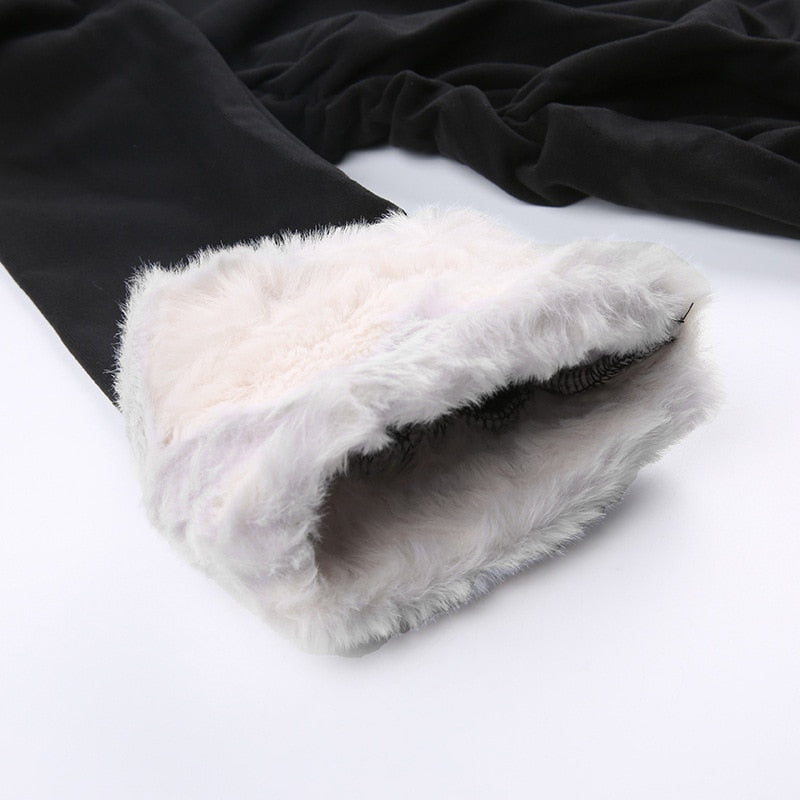 Black holiday mini dress with white fluffy cuffs and hem with a close view of the white fluffy sleeve cuff.