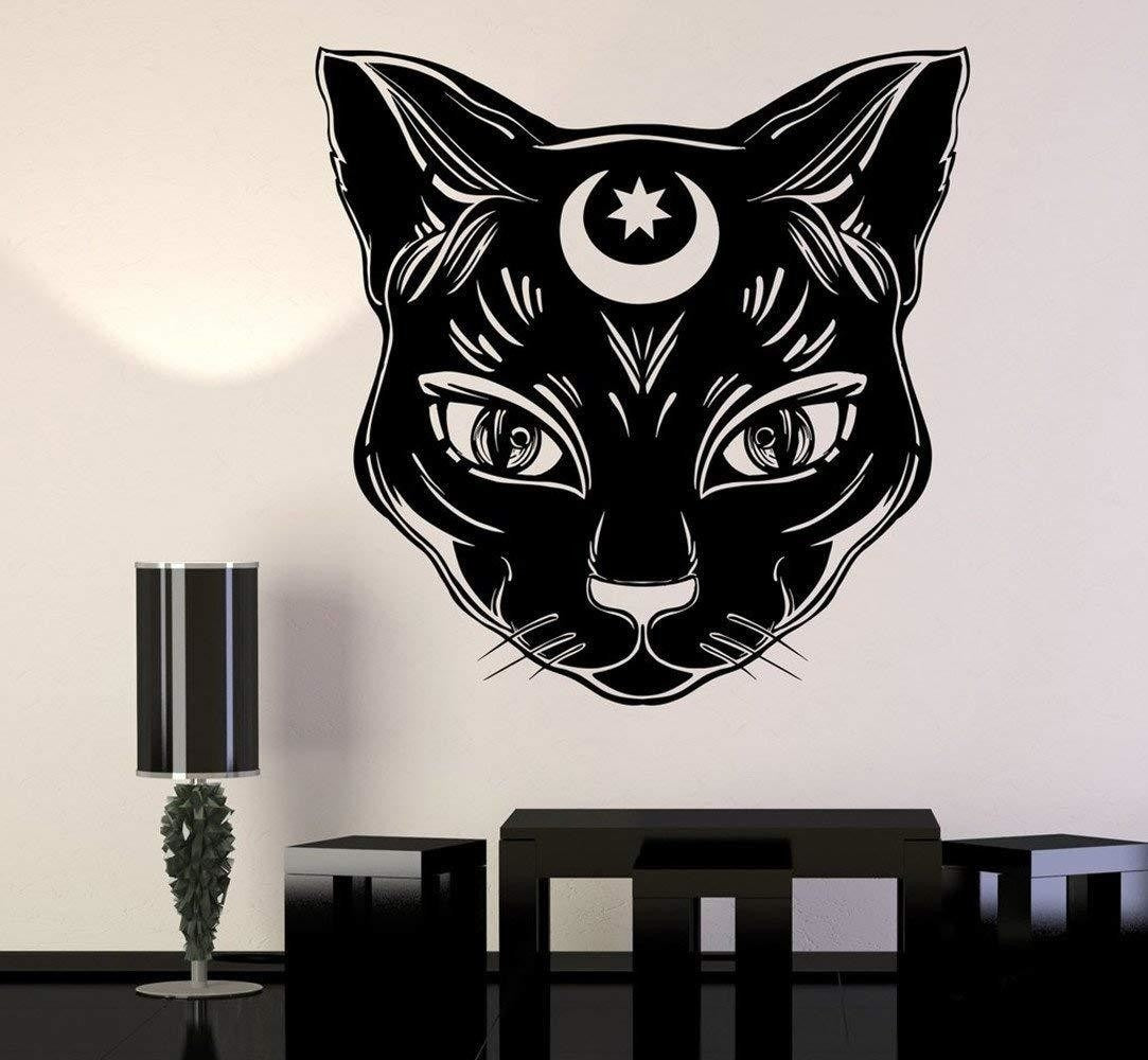 Black cat-face wall decal with pointed ears, fine fur lines and a crescent and star on its forehead. A dining-room mockup shows the design above a table.