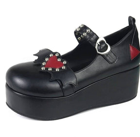 Black platform Mary Jane shoe with a red studded heart and black bat wings across the front strap, plus a heart-shaped buckle and thick wedge sole.