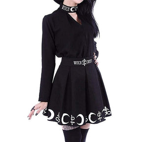 Black Witch Craft pleated skirt in a front outfit view with one hand on the waist and white crescent details along the hem.