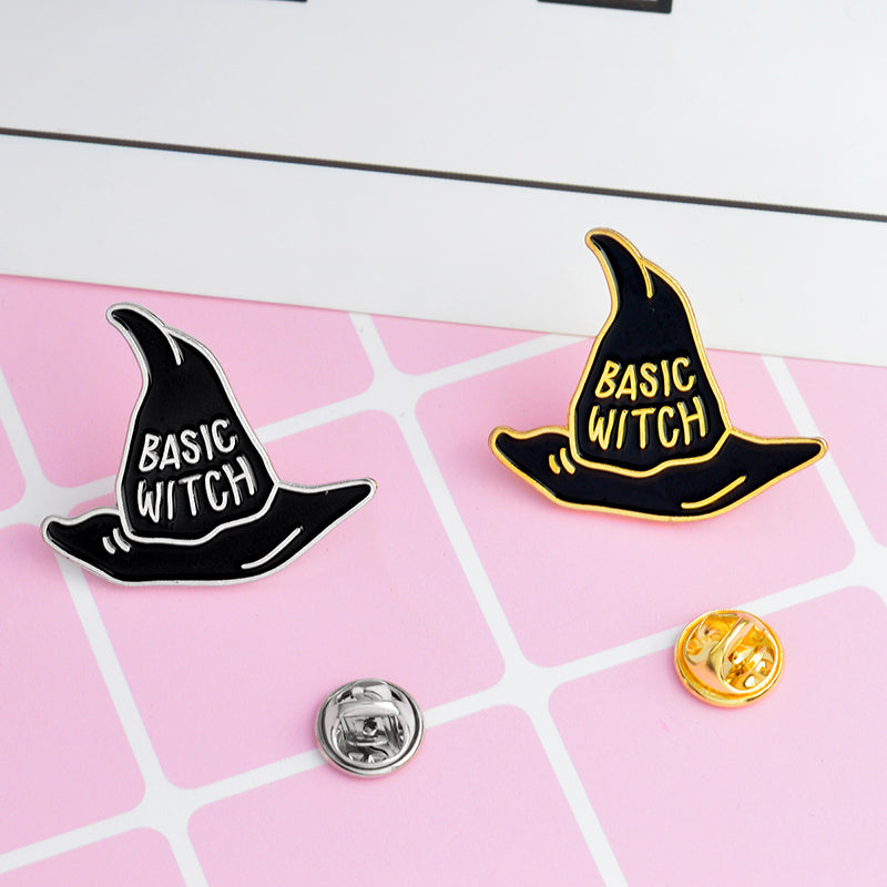 Black Basic Witch hat pins with gold-tone and silver-tone outlines on pink, beside their removable backs.