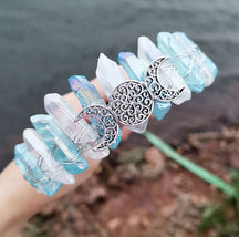 Angled view of a blue clear crystal point crown with a silver-tone triple moon emblem and wire-wrapped band.