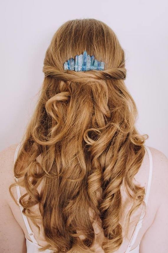 Blue crystal comb tucked into a half-up hairstyle, with the uneven stone row visible above the gathered hair.