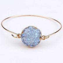 Blue druzy quartz circle cuff with an uneven glittering surface inside a gold-tone round setting.
