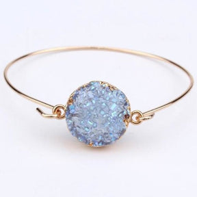 Blue druzy quartz circle cuff with an uneven glittering surface inside a gold-tone round setting.