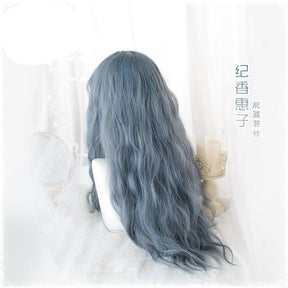 Rear view of the blue-gray wig worn loose, showing long waves and the blend of smoky blue and gray tones against a white decorative background.