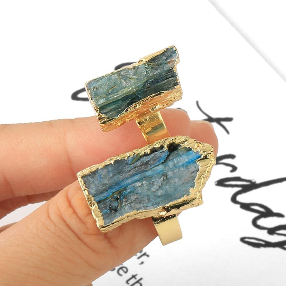 Repeated view of two kyanite rings on a hand, showing the different blue stone shapes side by side.