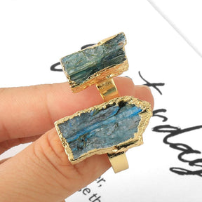 Two blue kyanite rings worn on fingers, with irregular striated stones and gold-tone borders.