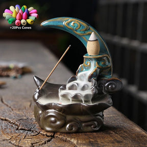 Blue and dark brown crescent moon burner with smoke flowing down the tiers, plus a graphic representing the 20 included incense cones.