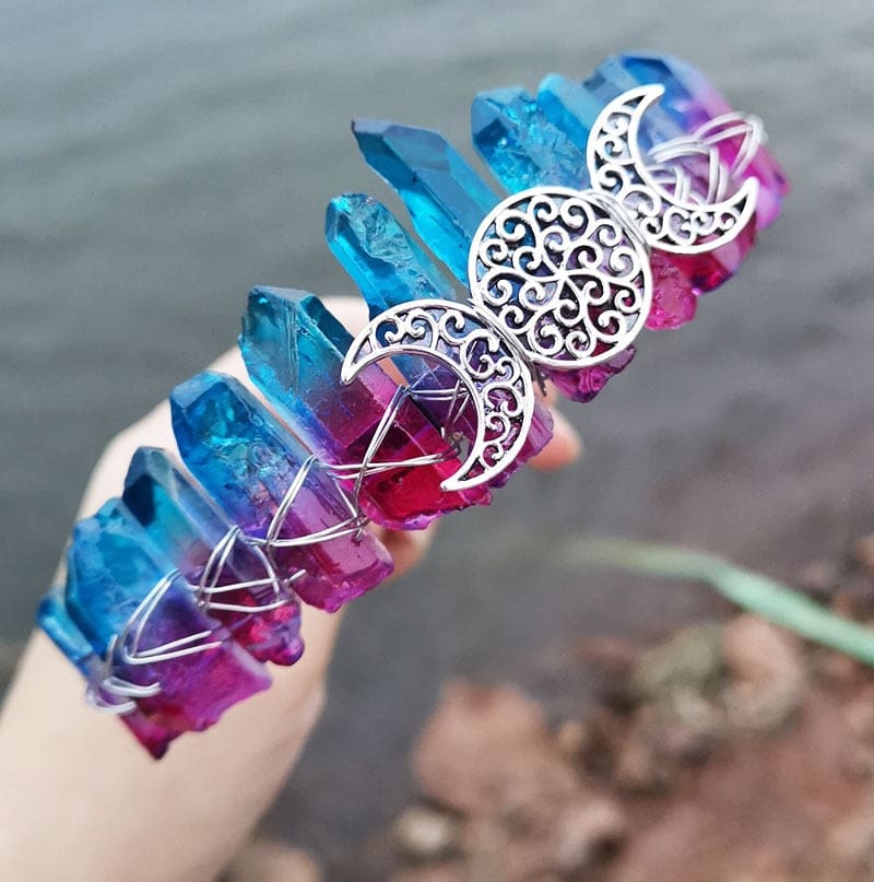 Angled view of a blue pink crystal point crown with a silver-tone triple moon emblem and wire-wrapped band.