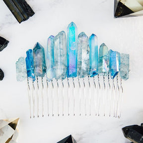 Blue quartz hair comb arranged flat with crystal display props, showing an uneven row of iridescent points above silver-tone teeth.
