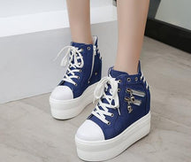 Blue high-top platform sneakers with white laces, toe caps and soles, worn on a pale tiled floor.