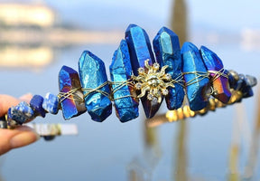 Blue crystal point tiara with a gold-tone sun face, radiating rays and wire-wrapped points along the curved band.