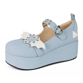 Blue platform Mary Jane shoe with white bat-wing details and a studded pale heart across the front, photographed from an angle on white.