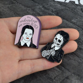 The pink slogan and monochrome skeleton pins resting in an open palm, showing their contrasting outlines and relative size.