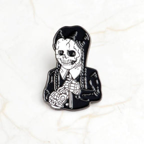 Black-and-white skeleton enamel pin with long braids, a pale shirt collar and dark skirt, isolated on white.