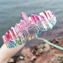 Angled view of a bright rainbow crystal point crown with a silver-tone triple moon emblem and wire-wrapped band.